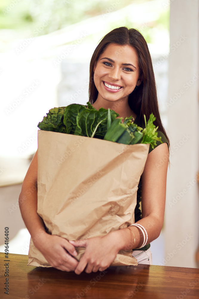 吃得好，感觉很棒。一个快乐的年轻女人的画像，她穿着ki拿着一袋杂货