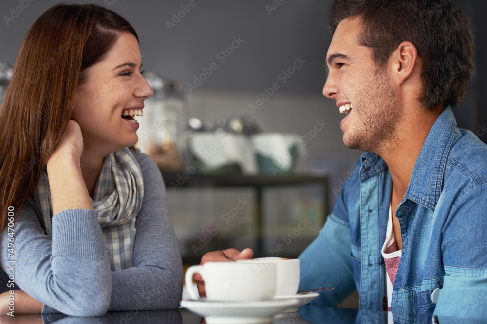 He always makes her smile. A loving young couple at a coffee shop together.
