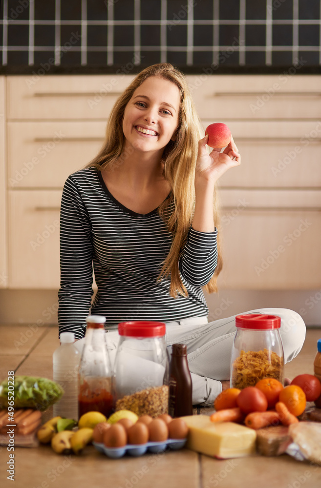 健康饮食从家里开始。一位迷人的年轻女性被各种食物包围的照片