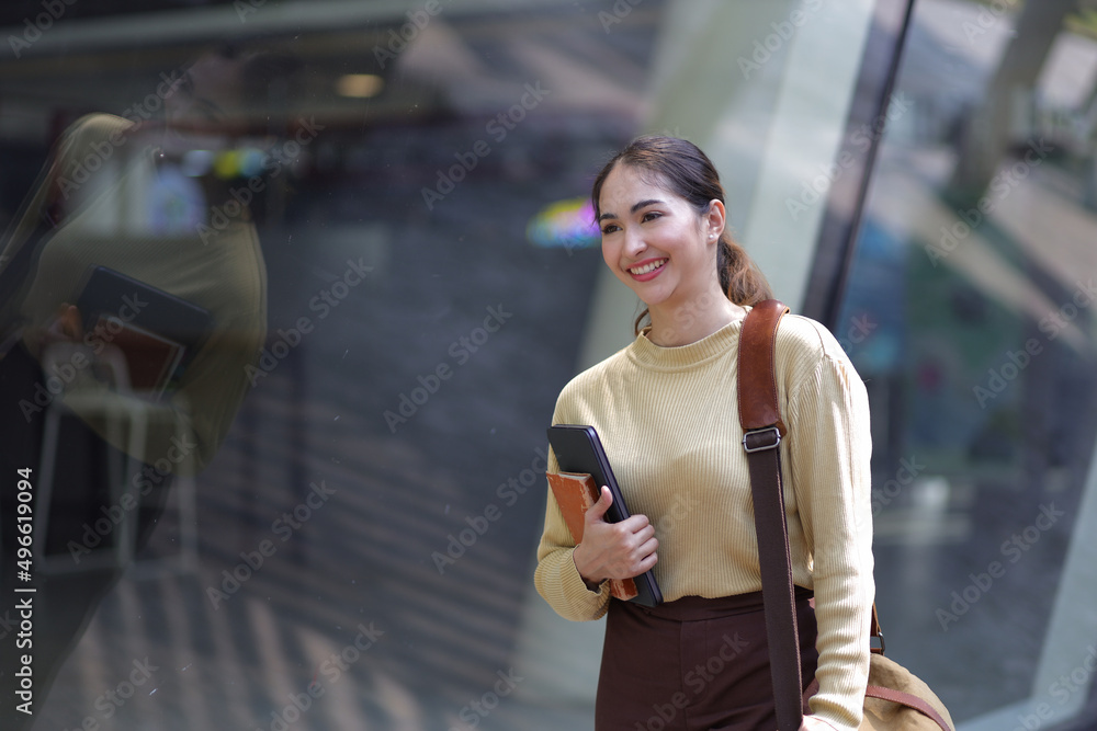 Portrait of a young business woman carrying luggage while walking at an airport or the center of a l