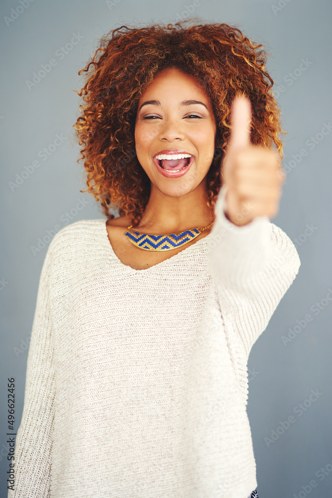 对幸福说是。一位年轻女性在灰色背景下竖起大拇指的肖像。