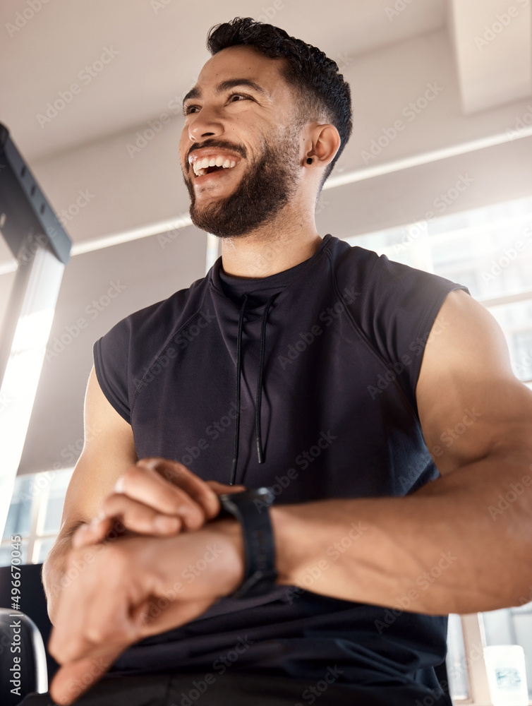 一如既往地竭尽全力。一个运动型年轻人在健身房锻炼时检查手表的镜头。