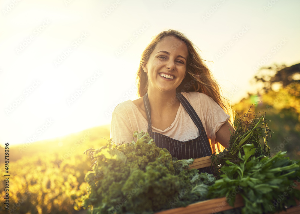 我是有机种植的。照片中一名年轻女子在远处拿着一箱新鲜采摘的农产品