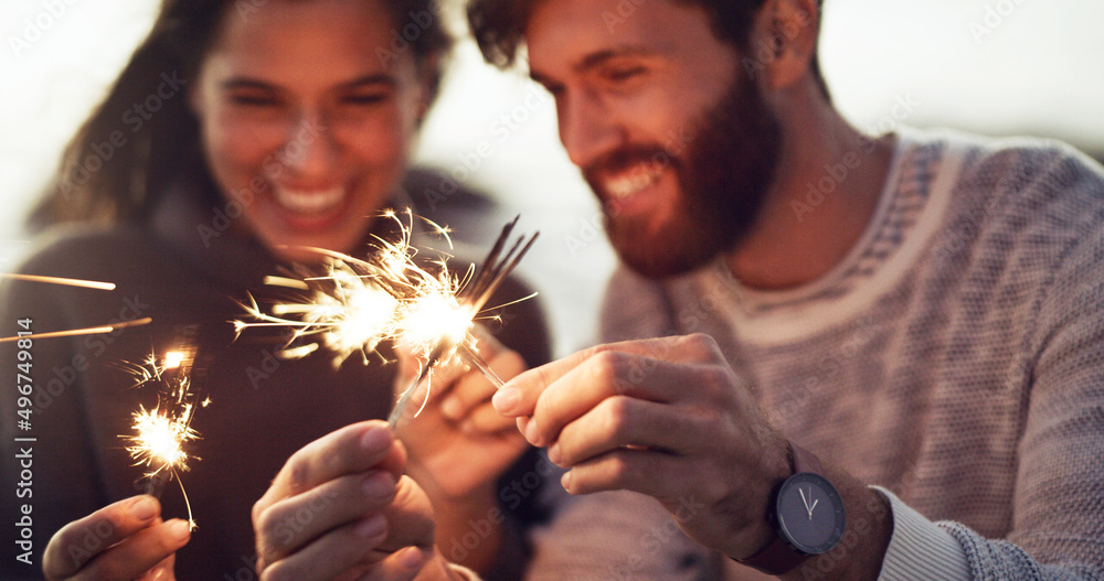 爱情是值得庆祝的。一对年轻夫妇在海滩上手持焰火的裁剪镜头。