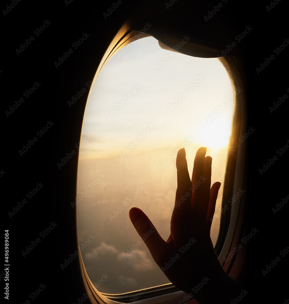 触摸天空。一张无法辨认的人手举着飞机窗户的照片。