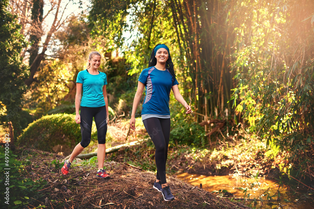 我们正在改善健康的路上。两位运动型年轻女性在大自然中锻炼的照片。