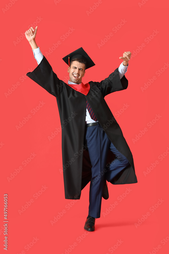 年轻的男毕业生在红底上跳舞