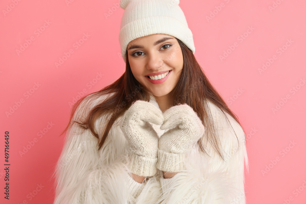 戴着粉色背景保暖手套和帽子的年轻女子