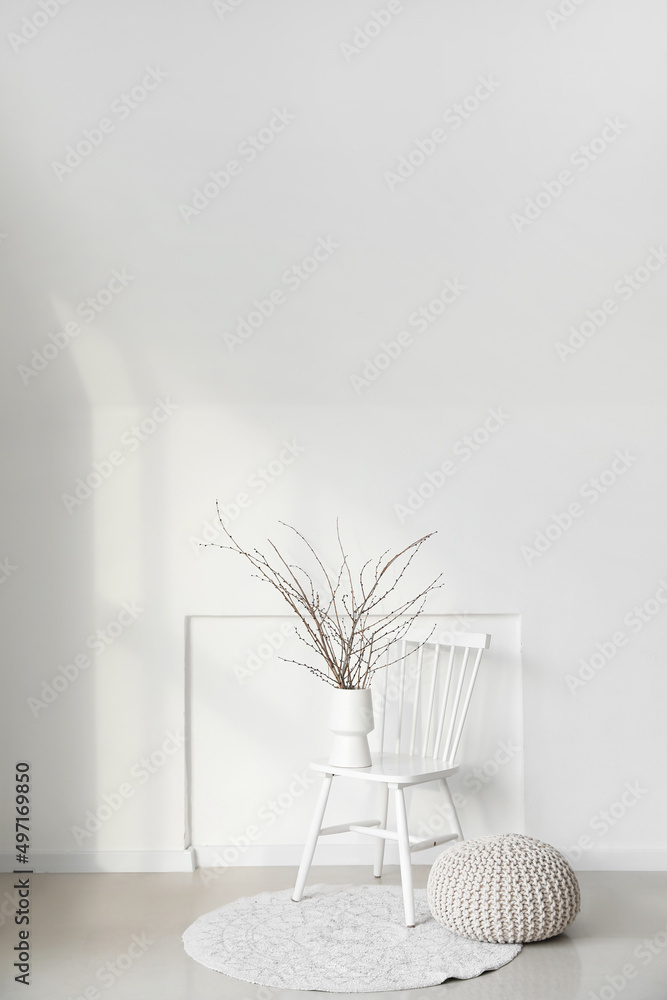 椅子上有树枝的花瓶，靠近浅色墙壁的花瓶