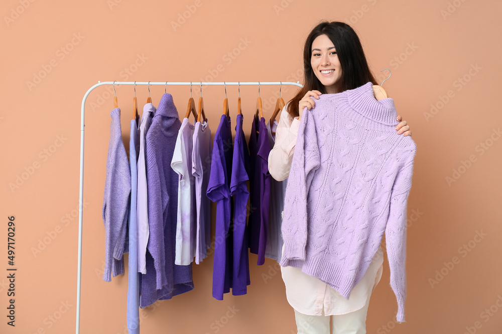 年轻的亚洲女人和架子，米色背景上有紫色的衣服