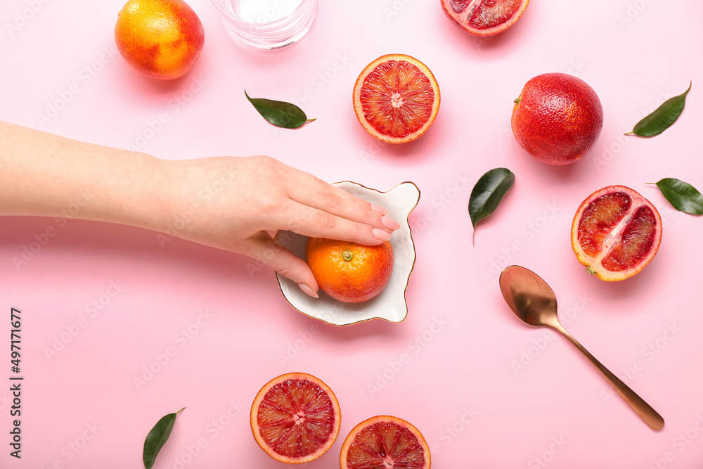 Woman squeezing fresh grapefruit on pink background