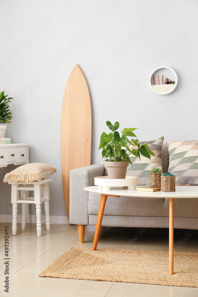 带木制冲浪板、桌子和沙发的浅色客厅内部