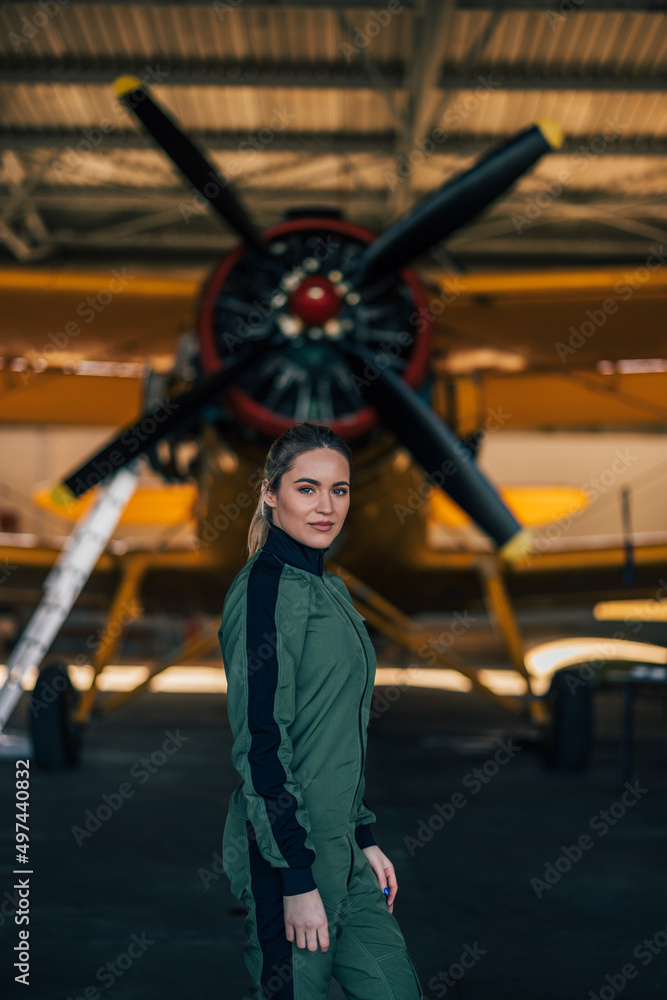 Portrait of serious caucasian aviator, standing in plane hangar, getting ready to fly.
