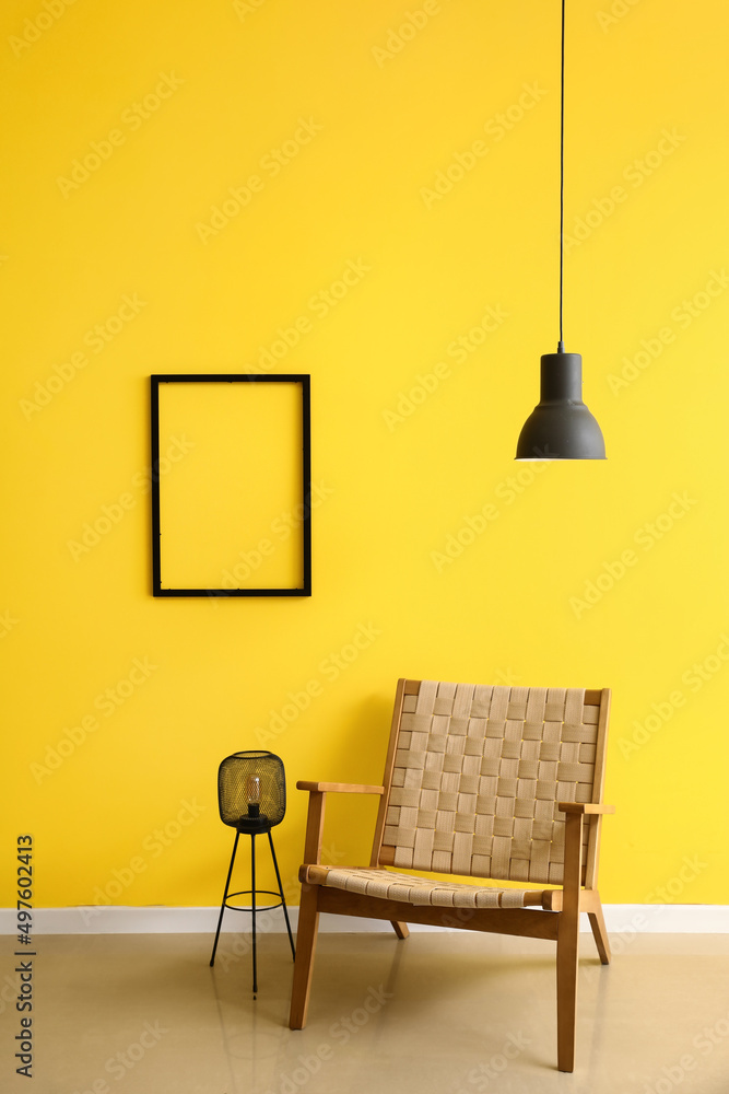 房间内部黄色墙上舒适的扶手椅、灯和空白相框
