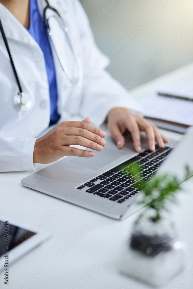 负责她的医疗实践。一名医生在办公室用笔记本电脑工作的特写镜头。