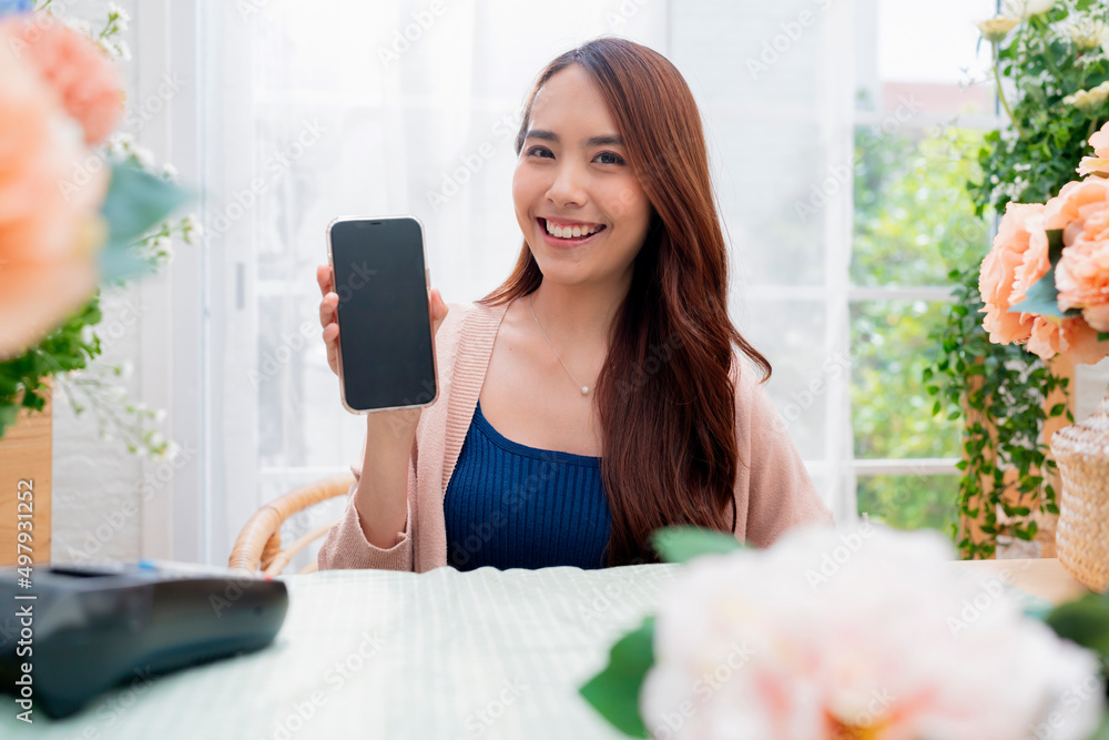 一家快乐的亚洲年轻成人花店的肖像，带着欢快微笑的手秀智能手机