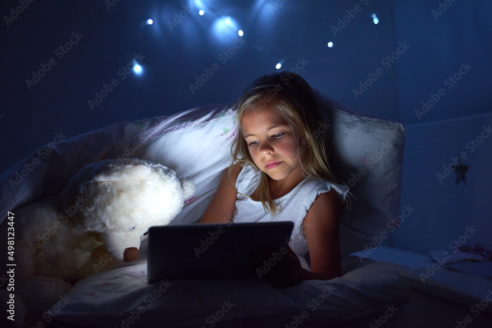 Curious about modern technology. Shot of a little girl using a digital tablet before bedtime.