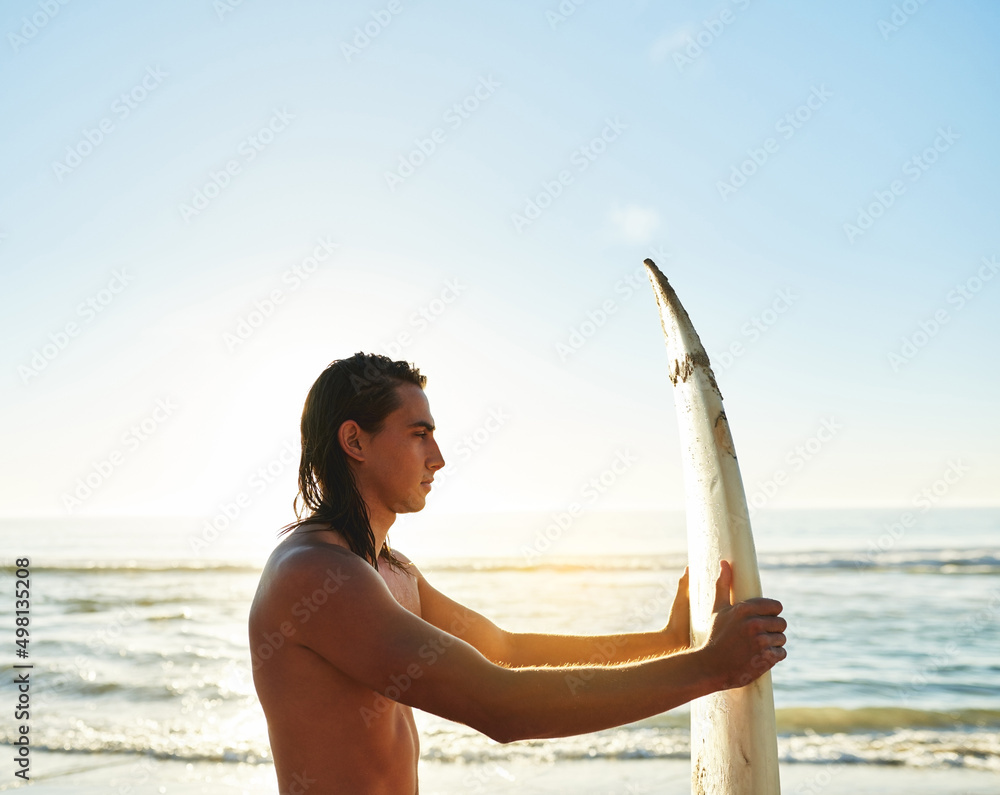 冲浪前必须检查冲浪板。一个英俊的年轻人抱着看的裁剪镜头