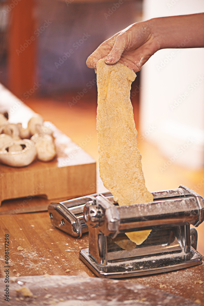 Pasta la vista。一个人在意大利面机上滚动新鲜面团的裁剪镜头。