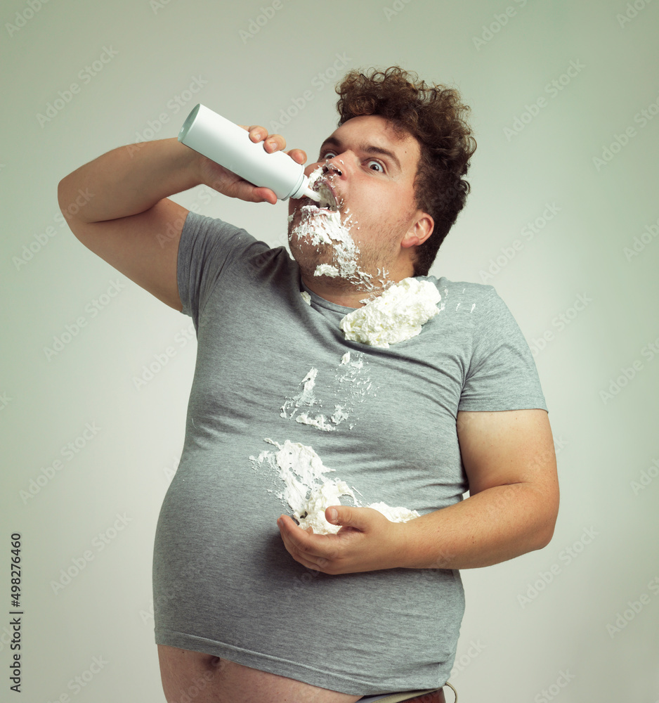 我的饮食习惯说我需要吃清淡的食物。一名超重男子用生奶油填满嘴里的照片