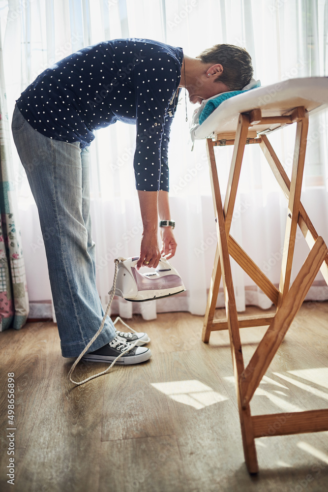 Weary from housework. Shot of a woman with her head down on a pile of clothes on an ironing board.