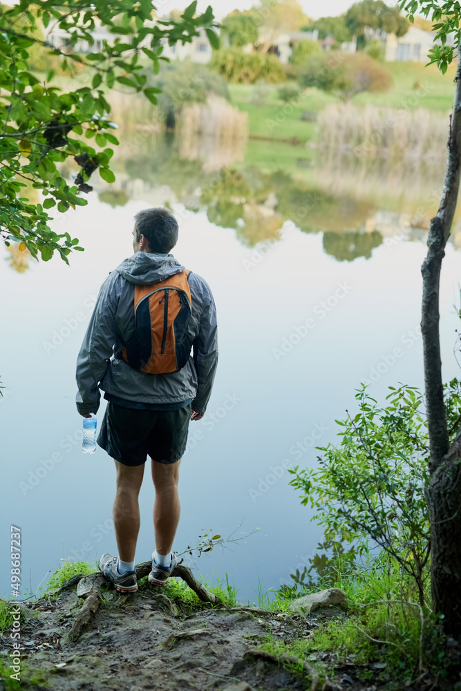 The views out here are unreal. Rearview shot of a young male athlete taking in the lake views while 