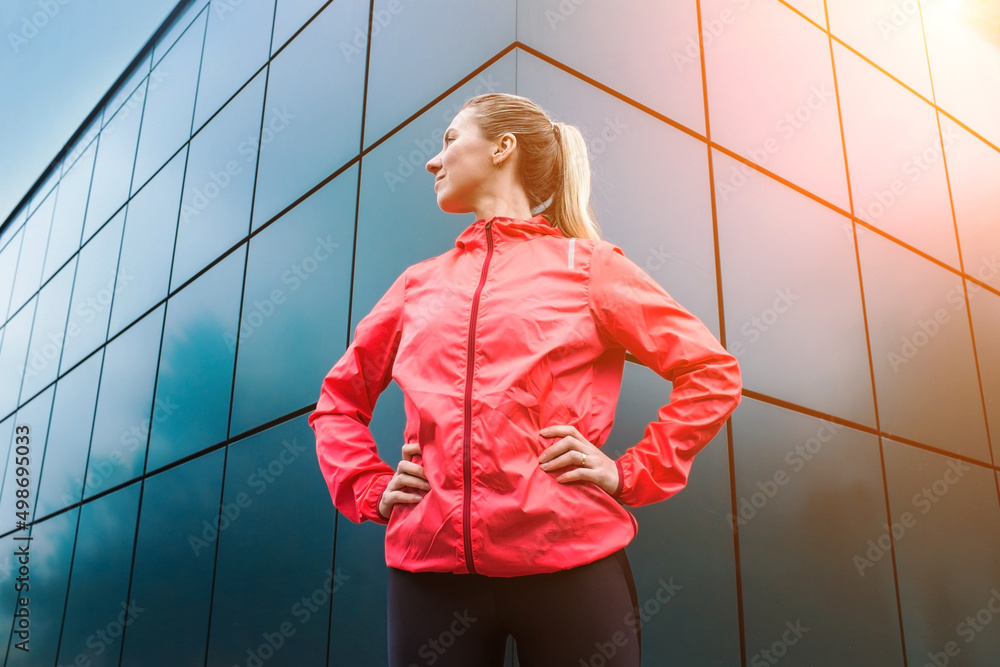 现代背景下在人行道上做运动的年轻女跑步者。运动服锻炼的女模特
