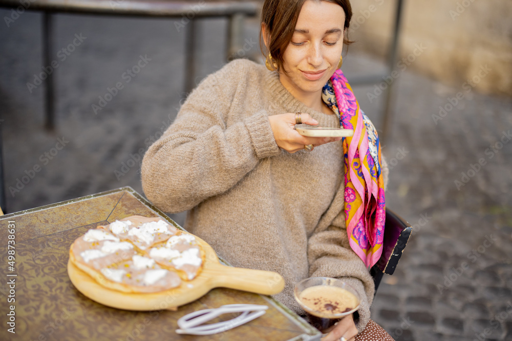 一名女子在户外餐厅与披萨共进午餐时，与著名的咖啡鸡尾酒shakerato合影