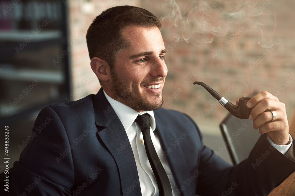 优雅而成功。一个时髦的商人在办公室抽烟斗的镜头。
