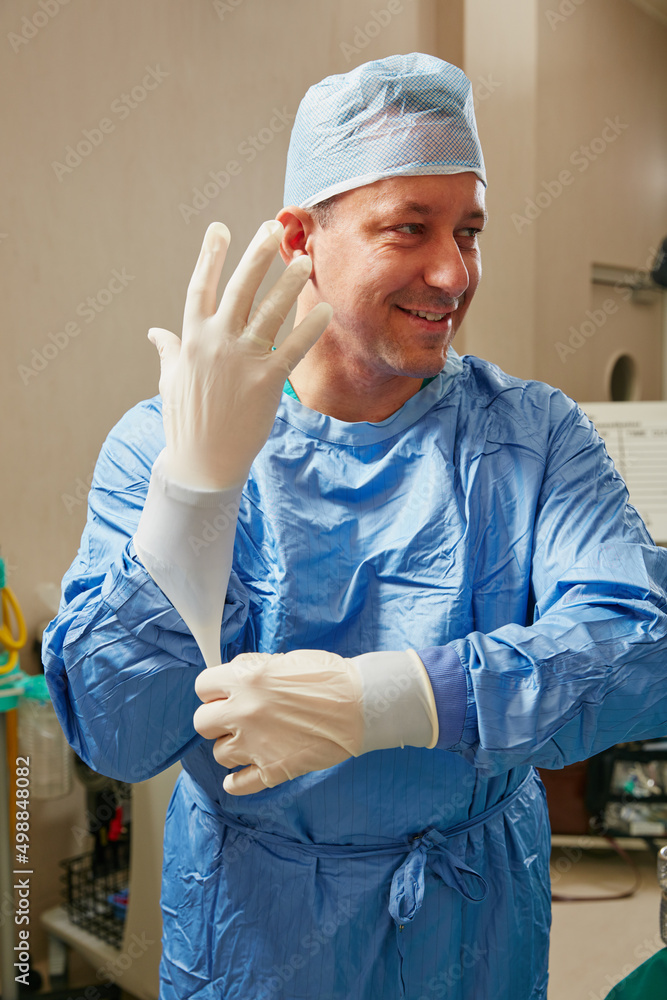 为急诊室带来多年的经验和积极性。外科医生戴上外科手套的镜头