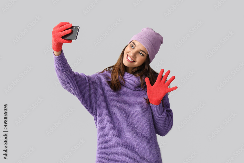 戴红色手套和帽子的年轻女子在浅色背景下自拍