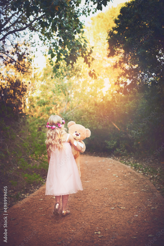 I wonder where this leads. Shot of a unrecognizable little girl walking with her teddy bear in the m