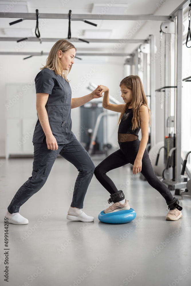 康复专家帮助小女孩在健身房锻炼。物理治疗的概念