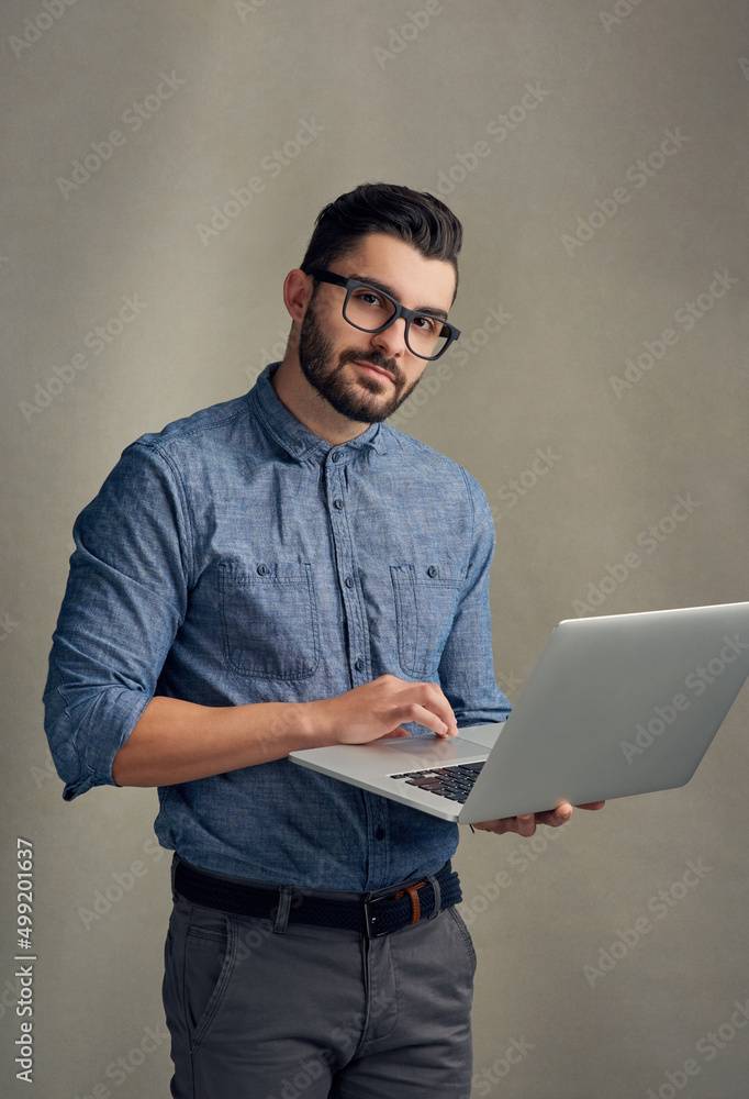 搜索你想要的任何东西。一个英俊年轻人在灰色背景下使用笔记本电脑的工作室肖像