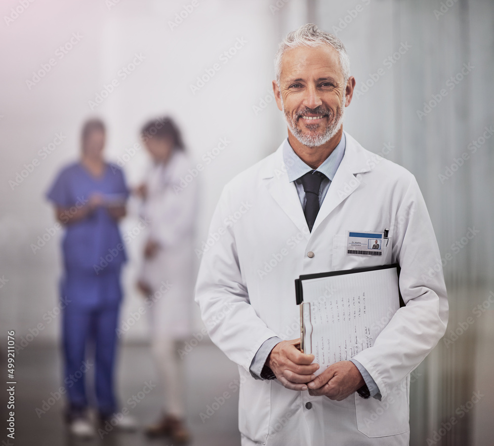 你的健康是我工作的目的。一位成熟的男医生和他的同事站在医院里的画像