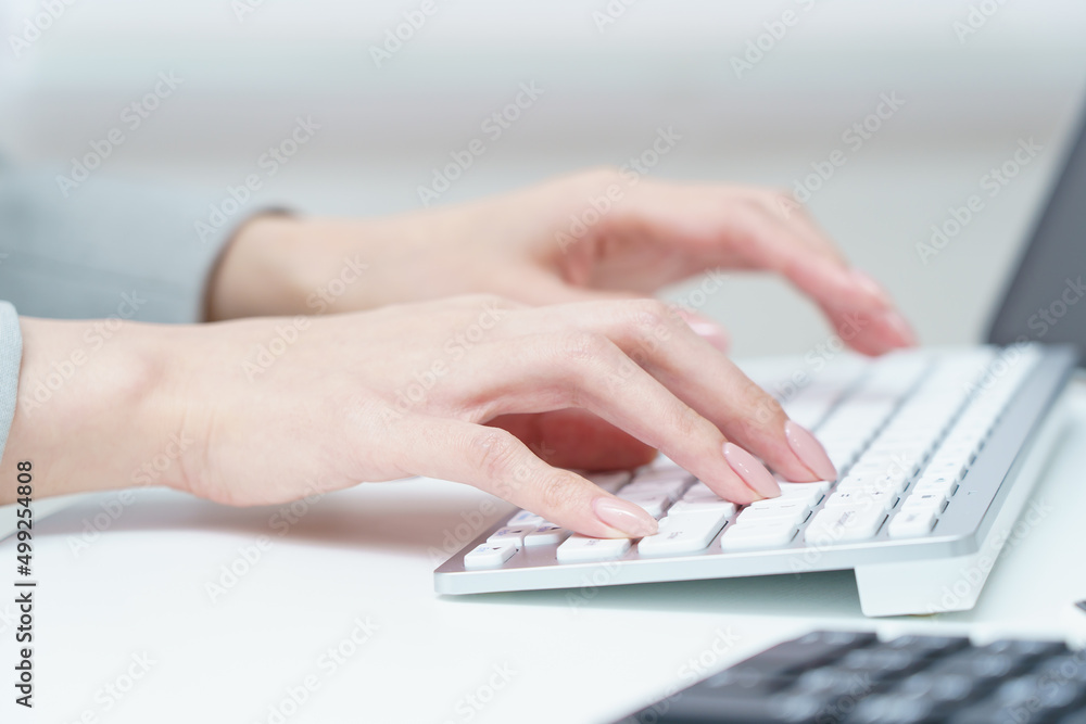 パソコンのキーボードを打つ女性の手元 