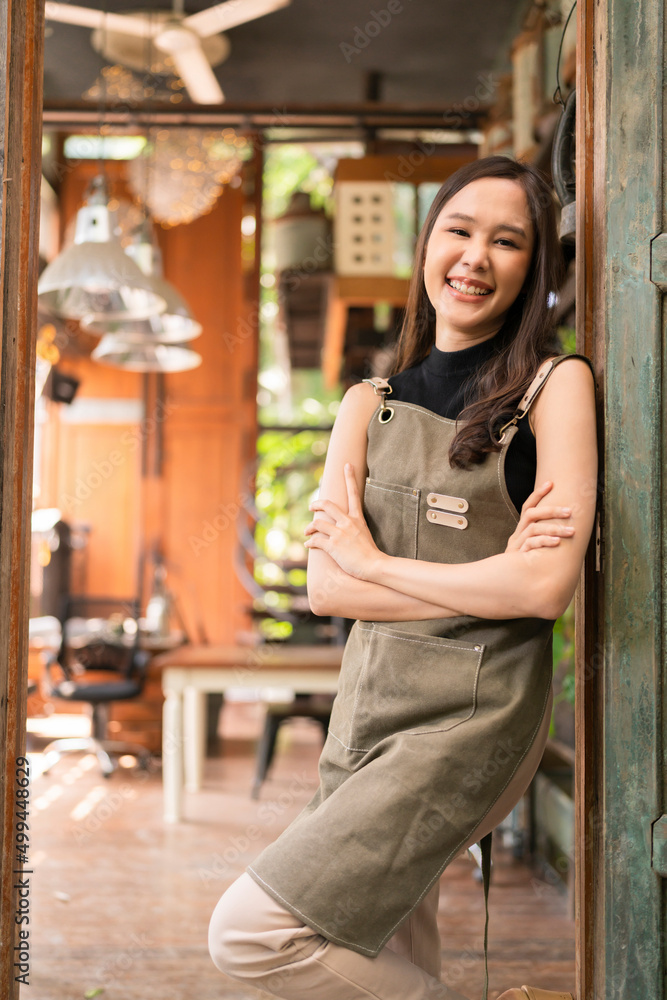 亚洲成年女性穿着围裙站在她的工作室陶艺工作室门口的肖像