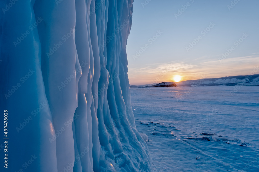 寒冷的冬季日落时，贝加尔湖的岩石上挂着冰柱