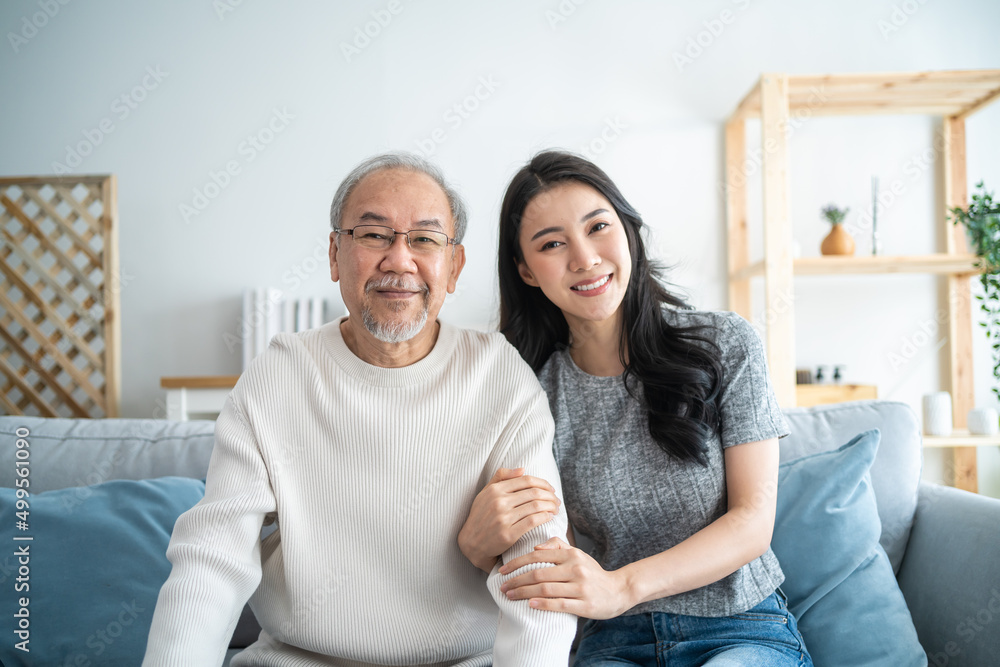 亚洲美丽女儿与年长父亲拥抱坐在一起的肖像