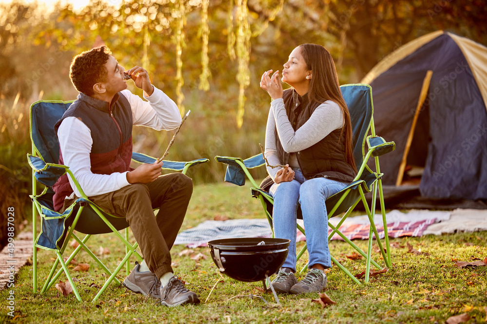 在树林里一切都很好。一对年轻夫妇在外面露营时烤棉花糖的镜头。