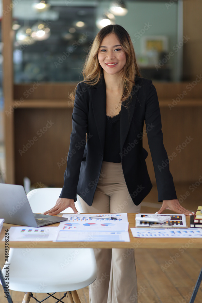 一位迷人的亚洲女商人或经理在办公室办公桌旁的肖像。美丽的秘书