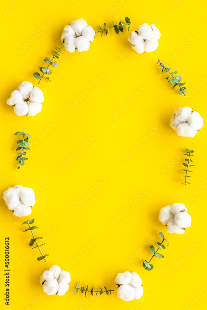 Flowers frame on yellow desk with fresh eucalyptus branches and cotton. Flat lay, top view, copy spa