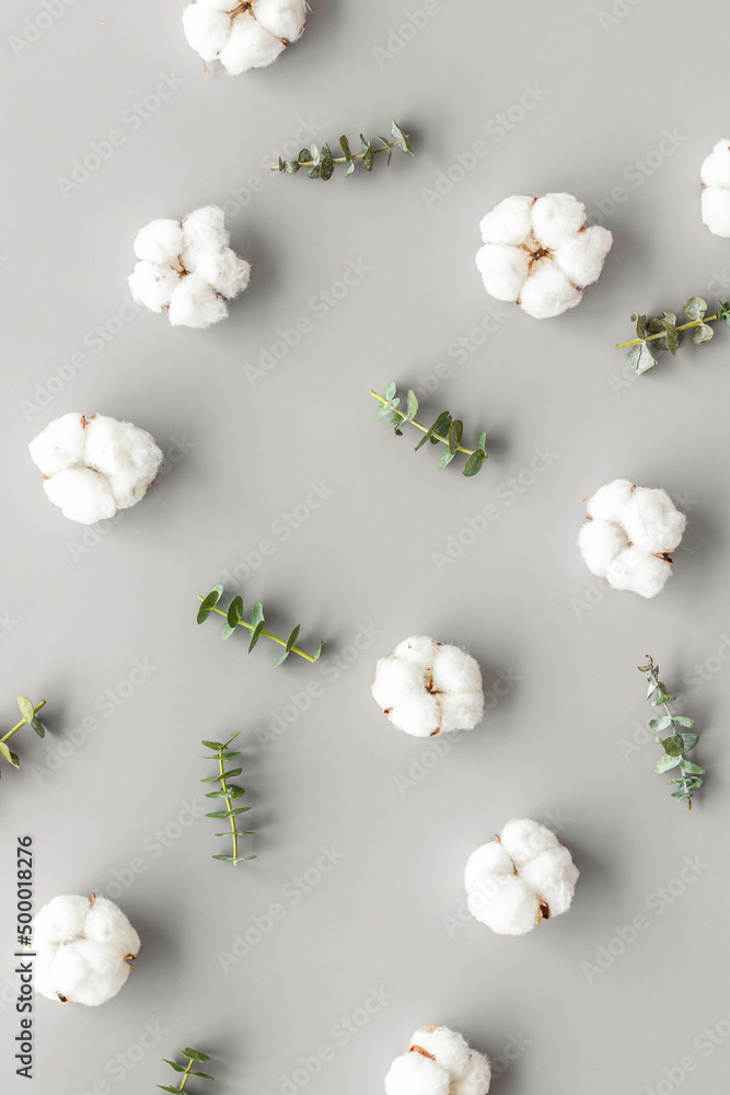Flowers composition on gray desk with eucalyptus branches and cotton. Flat lay, top view, copy space