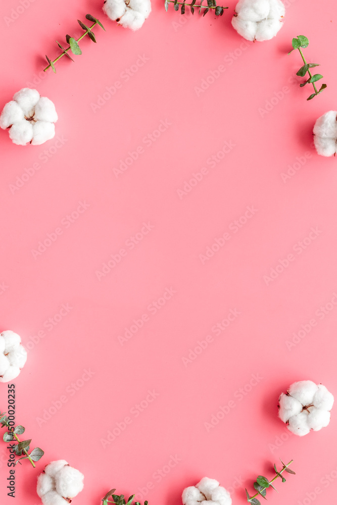 Flowers composition on pink desk with feucalyptus branches and cotton. Flat lay, top view, copy spac
