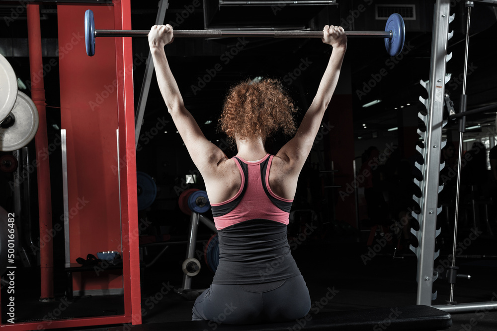 女健美运动员在健身房用杠铃锻炼