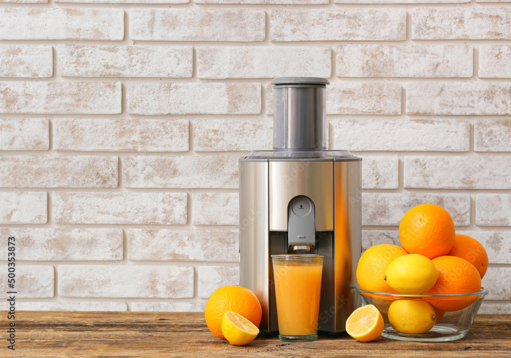新型现代榨汁机和木桌上的一杯带水果的新鲜果汁