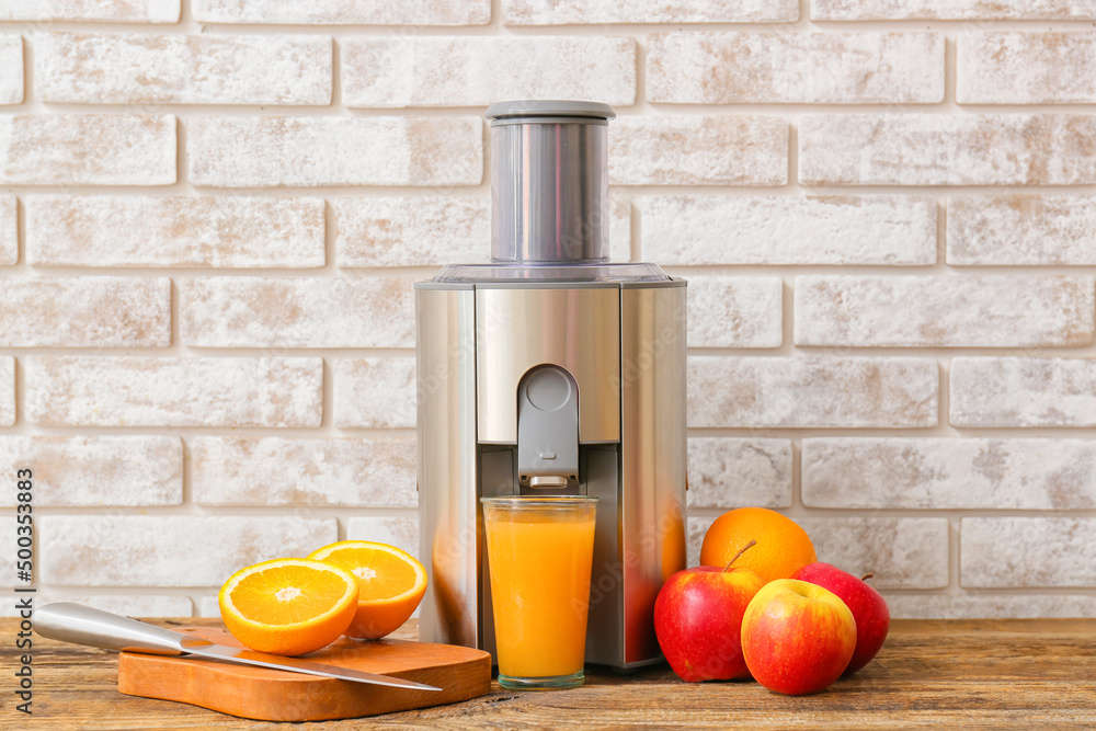 新的现代榨汁机和一杯新鲜果汁，木桌上有水果