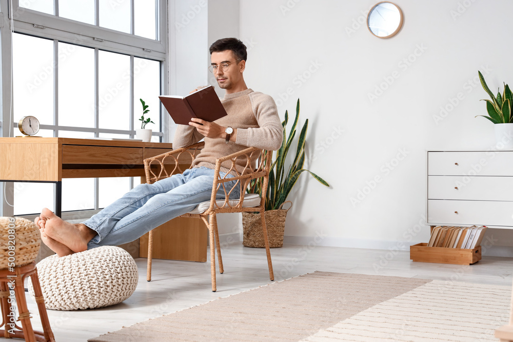 年轻的赤脚男人在家看书