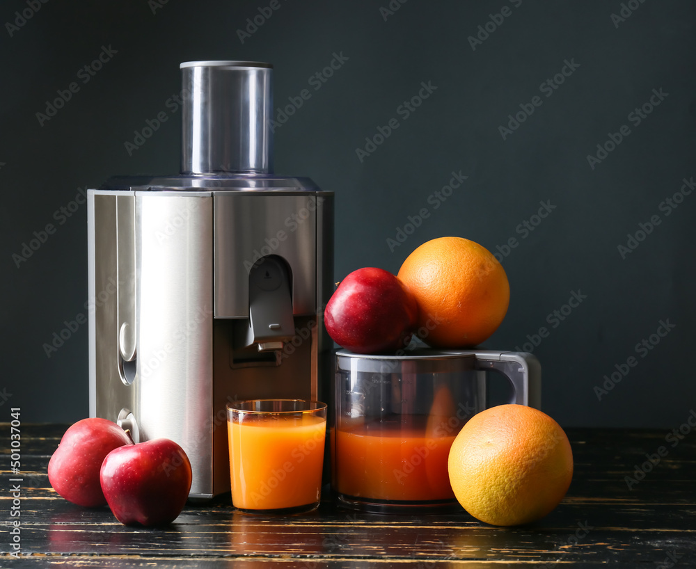 新型现代榨汁机和一杯深色木桌上的带水果的新鲜果汁