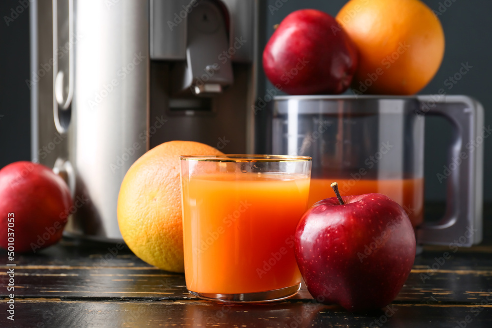 New modern juicer and glass of fresh juice with fruits on dark wooden table, closeup